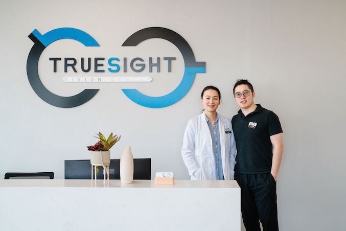 Image of staff standing at front desk with the Truesight logo behind them